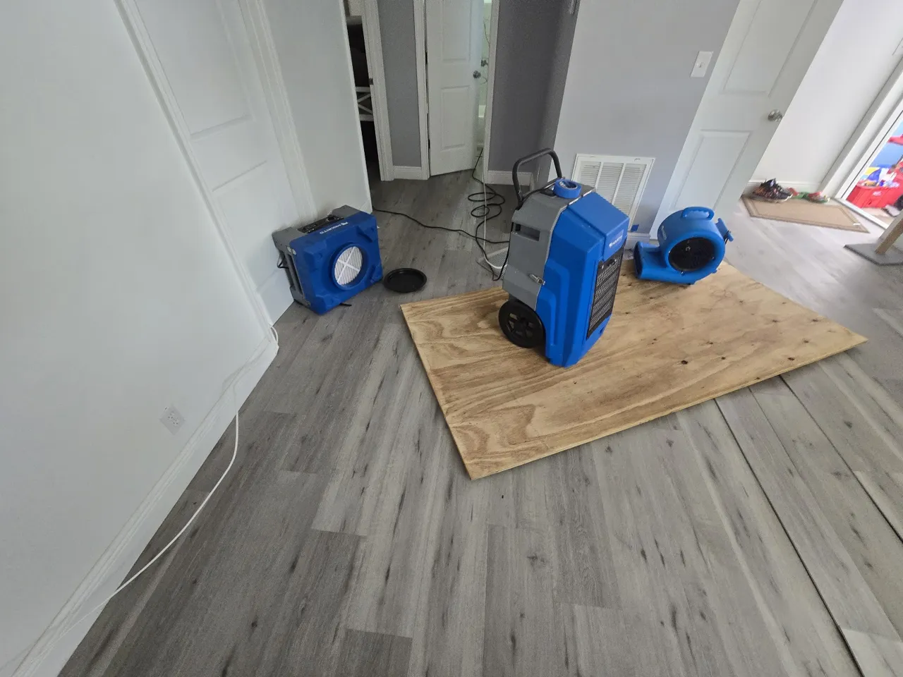 Commercial dehumidifier and air movers drying a water-damaged floor